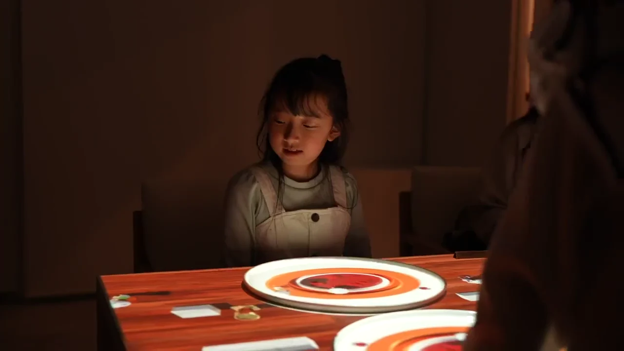 テーブルに映し出された光の演出を楽しむ子ども