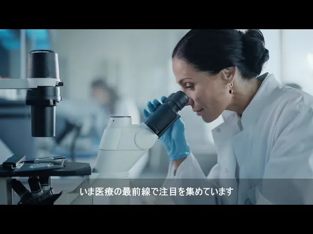 研究室で顕微鏡をのぞく研究者を映した商品PVの一場面